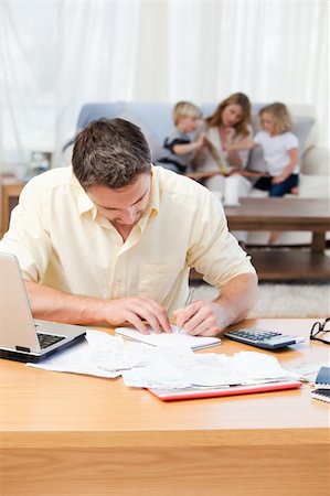 simsearch:400-05746763,k - Man calculating his bills while his family are on the sofa Stock Photo - Budget Royalty-Free & Subscription, Code: 400-04800924