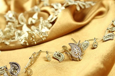simsearch:630-02220514,k - Background of gold cloth on which lay the golden jewelry Stockbilder - Microstock & Abonnement, Bildnummer: 400-04801657