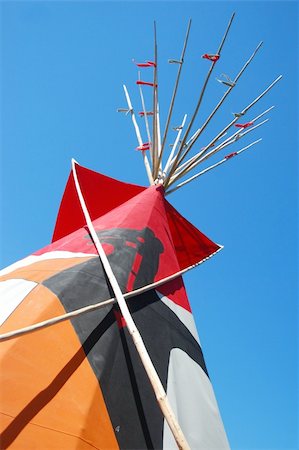 Partial view of top of Indian teepee decorated by bear colorfull painting and red ribbons. Against blue sky. Stockbilder - Microstock & Abonnement, Bildnummer: 400-04801899