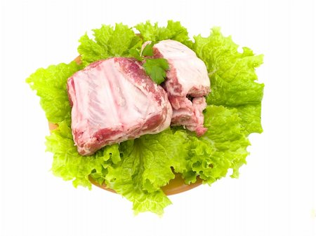 Some crude pork edges are located on the isolated plate decorated with leaves of green salad Stockbilder - Microstock & Abonnement, Bildnummer: 400-04802601
