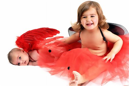 two sisters playing and smiling in studio wearing red angle wings Stockbilder - Microstock & Abonnement, Bildnummer: 400-04802677
