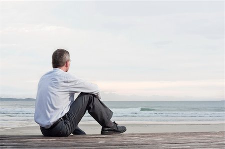 summer beach break - Thoughtful businessman sitting on a beach and looking at the sea Stock Photo - Budget Royalty-Free & Subscription, Code: 400-04803544