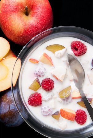 Glass bowl filled with yogurt mixed with fruit pieces arranged with spoon and some fruits around isolated on black background Stock Photo - Budget Royalty-Free & Subscription, Code: 400-04803978