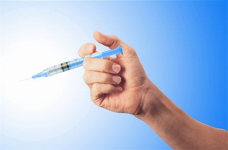 simsearch:400-05240096,k - Syringe in man's hand over blue background Fotografie stock - Microstock e Abbonamento, Codice: 400-04818190