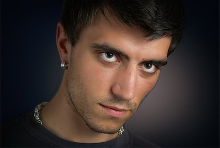 Portrait of beautiful and attractive young man with penetrating eyes and a silver earring in closeup on dark background Stock Photo - Budget Royalty-Free & Subscription, Code: 400-04813357
