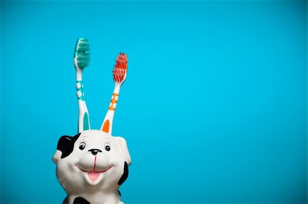 two toothbrushes in the glass resembling smiling dalmatian dog's head against blue background Fotografie stock - Microstock e Abbonamento, Codice: 400-04824245