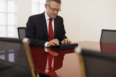simsearch:614-00655765,k - caucasian mid adult male manager typing on tablet pc in meeting room. Horizontal shape, side view, copy space Photographie de stock - Aubaine LD & Abonnement, Code: 400-04825581