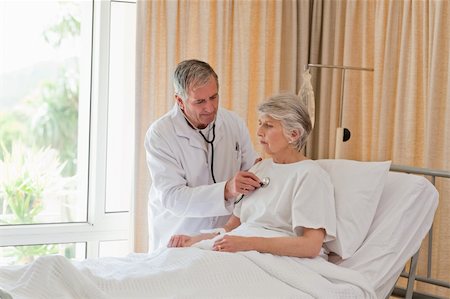 family visiting patient hospital bed - Senior doctor taking the heartbeat of his patient Stock Photo - Budget Royalty-Free & Subscription, Code: 400-04829877