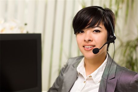 simsearch:400-04119293,k - Attractive Young Woman Smiles Wearing Headset Near Her Computer Monitor. Fotografie stock - Microstock e Abbonamento, Codice: 400-04823469