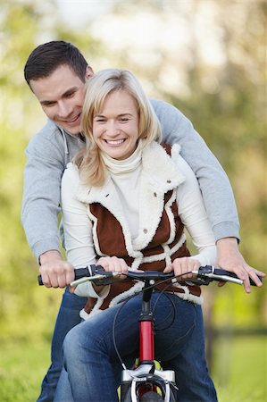 simsearch:400-04336561,k - Young couple rides a bicycle in the park Fotografie stock - Microstock e Abbonamento, Codice: 400-04837350
