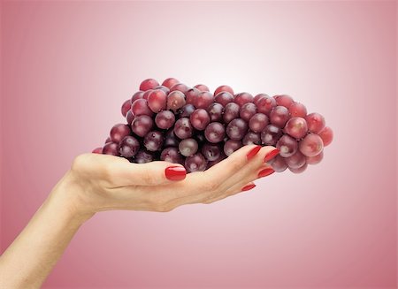 Red grapes in a female hand over red background Stock Photo - Budget Royalty-Free & Subscription, Code: 400-04839132