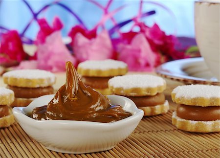 A Peruvian toffee-like cream called Manjar with Peruvian cookies called Alfajor and a coffee-cup as well as flowers in the background (Selective Focus, Focus on the cream) Stock Photo - Budget Royalty-Free & Subscription, Code: 400-04844594