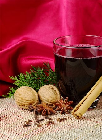 Hot spiced red wine with cinnamon, star anise, cloves, walnuts and a branch of evergreen with red background (Selective Focus) Stock Photo - Budget Royalty-Free & Subscription, Code: 400-04847198