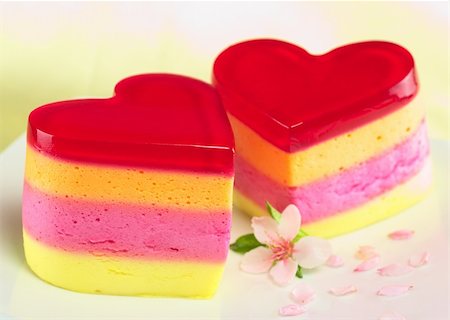 Colorful Peruvian heart-shaped jelly-pudding cakes called Torta Helada with a peach blossom on the plate (Selective Focus, Focus on the three upper lines on the front of the left cake) Stockbilder - Microstock & Abonnement, Bildnummer: 400-04848604
