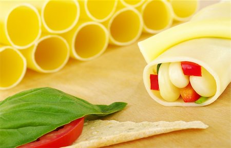 Cannelloni filled with vegetables on wooden board with Tomato, Mozzarella and Basil on Crocantini (Selective Focus) Stock Photo - Budget Royalty-Free & Subscription, Code: 400-04848674