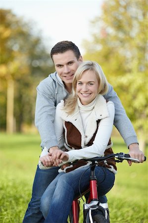 simsearch:400-04336549,k - Attractive young couple on a bicycle in the park Fotografie stock - Microstock e Abbonamento, Codice: 400-04840776