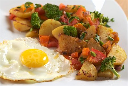 simsearch:400-04855335,k - Fried egg with fried potatoes, broccoli, carrot, tomato and onion and seasoned with fresh oregano (Selective Focus, Focus on the egg yolk and the front of the fried vegetables) Foto de stock - Royalty-Free Super Valor e Assinatura, Número: 400-04854597