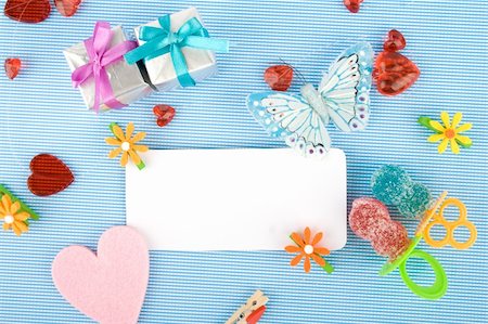 sunny_baby (artist) - Background for the holiday newborn blue. Pacifiers - candy, red hearts, a butterfly net and a white card Foto de stock - Royalty-Free Super Valor e Assinatura, Número: 400-04855310
