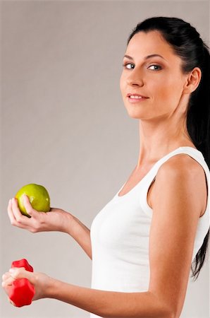 sporty woman is holding red barbell and green apple on grey background Stock Photo - Budget Royalty-Free & Subscription, Code: 400-04856418