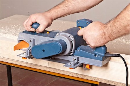 simsearch:400-04856931,k - Close-up of a construction worker's hand and power tool while planing a piece of wood trim for a project. Photographie de stock - Aubaine LD & Abonnement, Code: 400-04856929