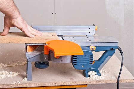 simsearch:400-04856931,k - Close-up of a construction worker's hand and power tool while planing a piece of wood trim for a project. Photographie de stock - Aubaine LD & Abonnement, Code: 400-04856930