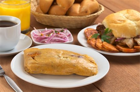 simsearch:400-04855335,k - Peruvian breakfast with tamal (cooked corn with meat) and pan con chicharron (bun with fried pork meat), salsa criolla (onion salad), coffee, orange juice and bread (Selective Focus, Focus on the front of the tamal) Foto de stock - Royalty-Free Super Valor e Assinatura, Número: 400-04859667