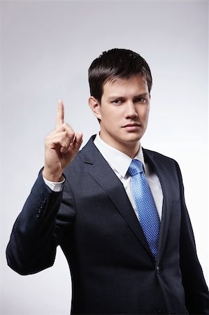 Attractive man in a suit with the index finger up on a gray background Photographie de stock - Aubaine LD & Abonnement, Code: 400-04850888