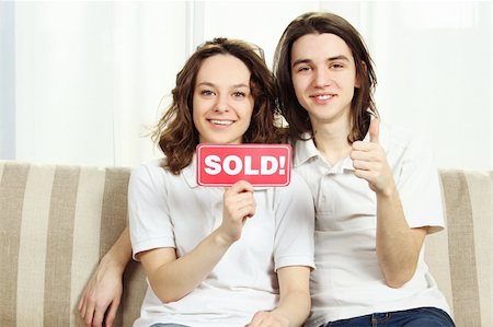 family with sold sign - Closeup of a couple sitting at home on the couch laughing, hugging and holding a plate sold Stock Photo - Budget Royalty-Free & Subscription, Code: 400-04851914