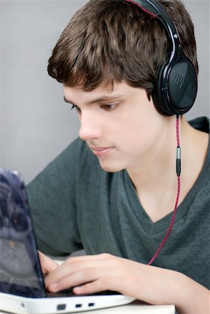 simsearch:400-05013654,k - Close-up of a teen wearing headphones working on his netbook. Photographie de stock - Aubaine LD & Abonnement, Code: 400-04851918