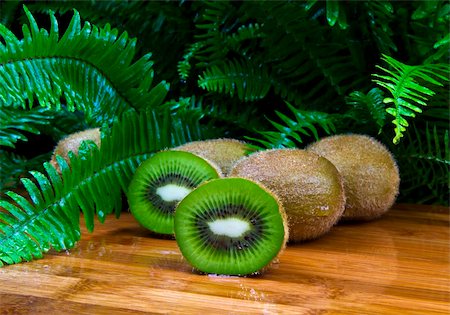 simsearch:400-05303673,k - Ripe kiwi halves and wholes on bamboo setting with Ferns in background Photographie de stock - Aubaine LD & Abonnement, Code: 400-04852711