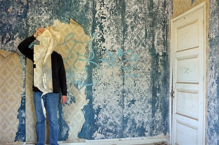 simsearch:400-05352563,k - Male figure behind torn wallpaper shred in abandoned building interior. Fotografie stock - Microstock e Abbonamento, Codice: 400-04853489