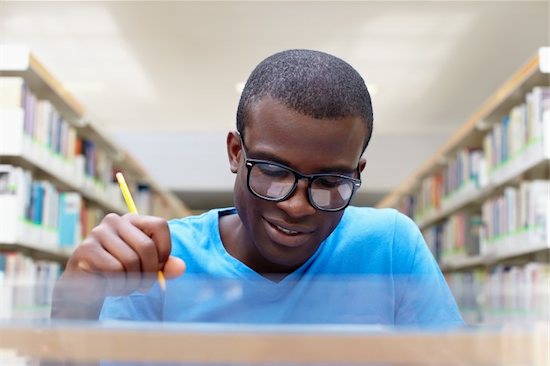 african american male college student sitting at desk in library and reading book. Reflections of paperwork on eyeglasses. Horizontal shape, front view Stock Photo - Royalty-Free, Artist: diego_cervo, Image code: 400-04864765