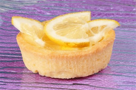 simsearch:400-05341443,k - Closeup of a mini lemon fruit tart on a glass plate over a pink background. With copy-space. Selective focus. Stockbilder - Microstock & Abonnement, Bildnummer: 400-04864770
