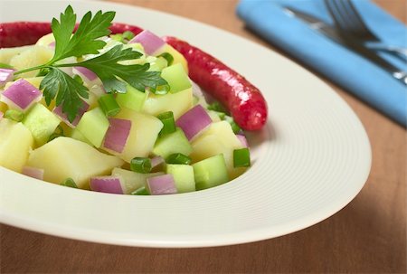 simsearch:400-04855321,k - Potato salad with cucumber, red and green onions with oil dressing garnished with parsley and served with small sausages in the back (Selective Focus, Focus on the parsley and the salad around) Stock Photo - Budget Royalty-Free & Subscription, Code: 400-04866014