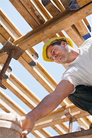 Authentic construction worker bending over under formwork girders to collect a bucket Foto de stock - Super Valor sin royalties y Suscripción, Código: 400-04866354