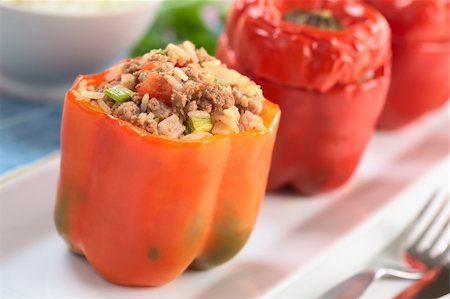 Baked stuffed red bell pepper filled with ground meat, onion, rice, tomato and green onion served on a long plate (Selective Focus, Focus on the tomato piece and the stuffing around it on the top) Stock Photo - Budget Royalty-Free & Subscription, Code: 400-04869534