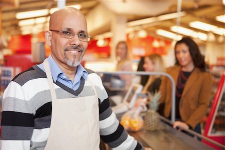 supermarket cashier smile - Portrait of a happy cashier with customer in the background Stock Photo - Budget Royalty-Free & Subscription, Code: 400-04860004