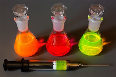simsearch:649-07279762,k - Three multi-coloured fluorescing flasks and a syringe on a dark grey background. Stock Photo - Budget Royalty-Free & Subscription, Code: 400-04874909