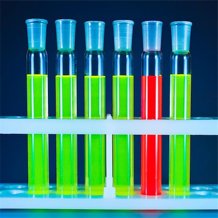 Five test tubes with a green fluorescing liquid and one with a red liquid in a support on a dark blue background. Stockbilder - Microstock & Abonnement, Bildnummer: 400-04874910