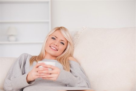 Gorgeous blond woman lying on a sofa relaxing on a line of tablet computers in the living room Photographie de stock - Aubaine LD & Abonnement, Code: 400-04870919
