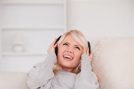 simsearch:400-04418454,k - Beautiful young blond woman with headphones lying in a sofa in the living room Foto de stock - Royalty-Free Super Valor e Assinatura, Número: 400-04870924