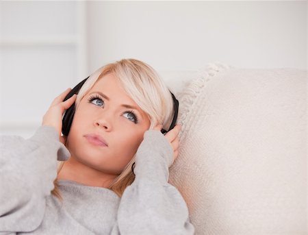 simsearch:400-04418454,k - Attractive young blond woman with headphones lying in a sofa in the living room Foto de stock - Royalty-Free Super Valor e Assinatura, Número: 400-04870925