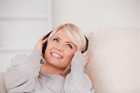 simsearch:400-04418454,k - Charming young blond woman with headphones lying in a sofa in the living room Foto de stock - Royalty-Free Super Valor e Assinatura, Número: 400-04870926