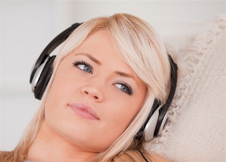 simsearch:400-04418454,k - Attractive happy blond woman with headphones lying in a sofa in the living room Stockbilder - Microstock & Abonnement, Bildnummer: 400-04870927