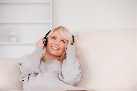 simsearch:400-04418454,k - Attractive blond woman with headphones lying in a sofa in the living room Foto de stock - Royalty-Free Super Valor e Assinatura, Número: 400-04870920