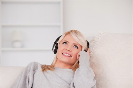 simsearch:400-04418454,k - Pretty blond woman with headphones lying in a sofa in the living room Stockbilder - Microstock & Abonnement, Bildnummer: 400-04870922