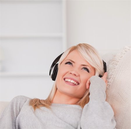 simsearch:400-04418454,k - Pretty young blond woman with headphones lying in a sofa in the living room Foto de stock - Royalty-Free Super Valor e Assinatura, Número: 400-04870923