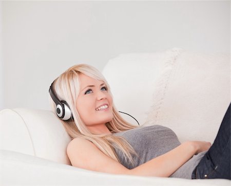 simsearch:400-04418452,k - Happy young blond woman with headphones lying in a sofa in a studio Photographie de stock - Aubaine LD & Abonnement, Code: 400-04870934