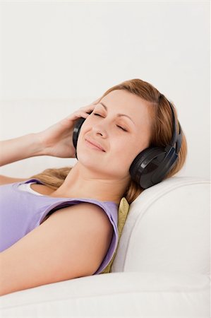 simsearch:400-04418452,k - Happy blond-haired woman listening to music lying on the sofa in the living-room Photographie de stock - Aubaine LD & Abonnement, Code: 400-04871205