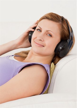 simsearch:400-04418452,k - Attractive blond-haired woman listening to music lying on the sofa in the living-room Photographie de stock - Aubaine LD & Abonnement, Code: 400-04871202